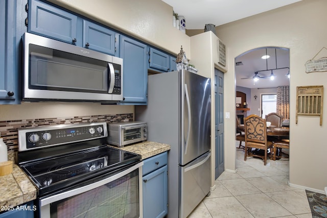 kitchen with light tile patterned flooring, blue cabinets, appliances with stainless steel finishes, pendant lighting, and backsplash