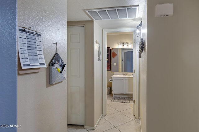 corridor featuring sink and light tile patterned flooring