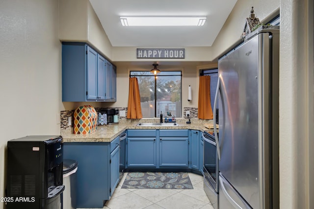 kitchen featuring stainless steel appliances, tasteful backsplash, sink, and blue cabinetry