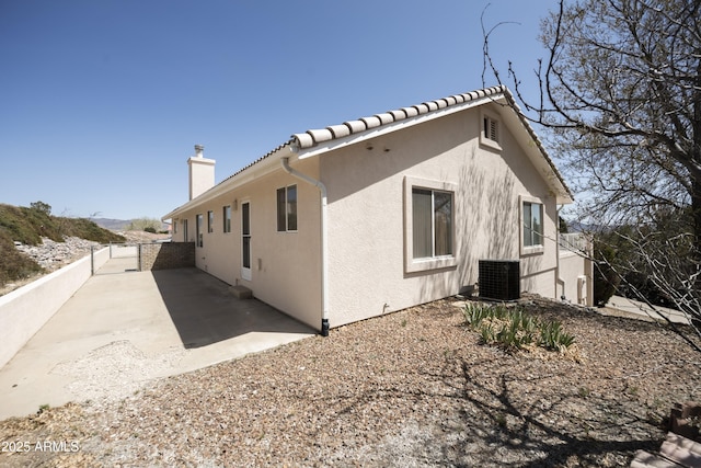 11430 E Manzanita Trl, Dewey, AZ 86327 - view of side of home with stucco siding, a chimney, central AC unit, and a patio