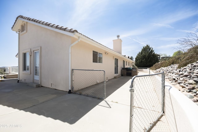 11430 E Manzanita Trl, Dewey, AZ 86327 - view of home's exterior with a gate, a chimney, stucco siding, and a patio area