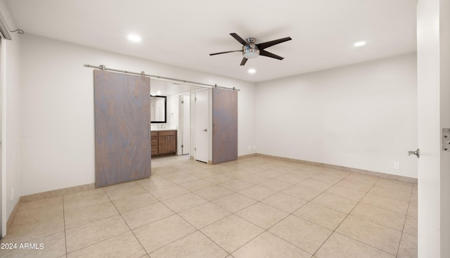 7012 N 22nd St, Phoenix, AZ 85020 - unfurnished bedroom featuring a barn door, ensuite bathroom, ceiling fan, and light tile patterned floors