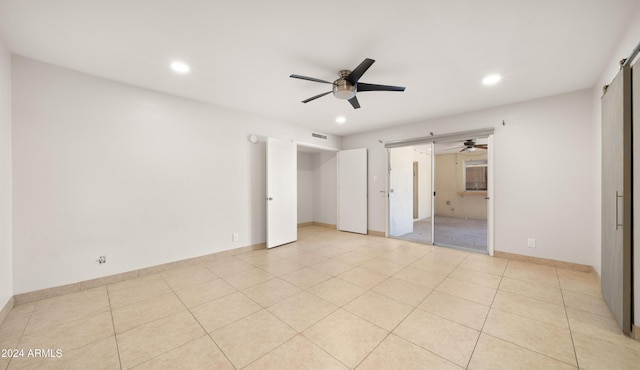 7012 N 22nd St, Phoenix, AZ 85020 - unfurnished bedroom featuring connected bathroom, a barn door, ceiling fan, and light tile patterned floors