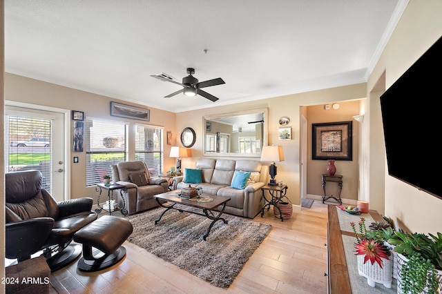 living room featuring plenty of natural light, ceiling fan, crown molding, and light hardwood / wood-style flooring