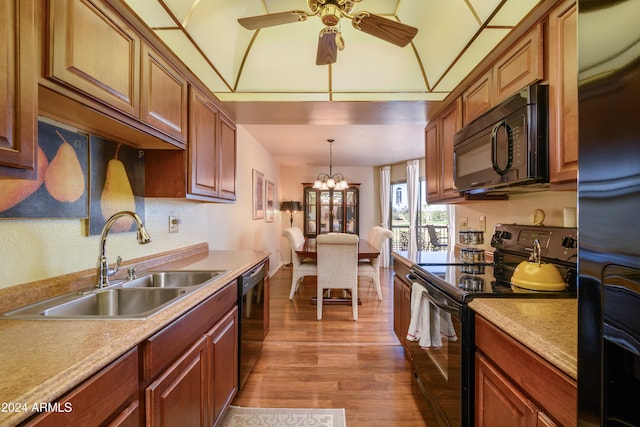 kitchen featuring sink, black appliances, pendant lighting, hardwood / wood-style floors, and lofted ceiling