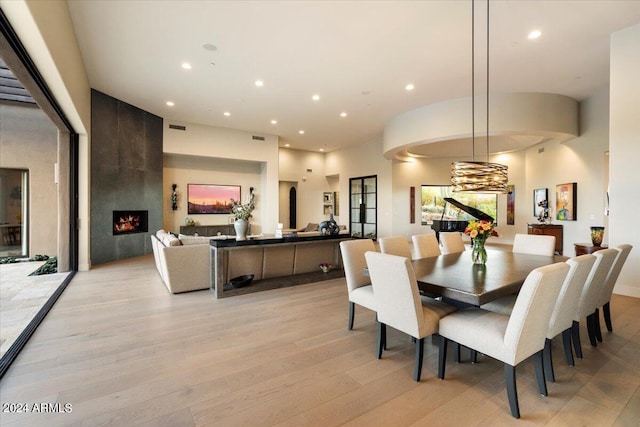 dining space with light wood-type flooring and a large fireplace