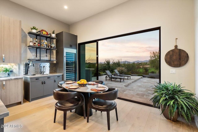 dining area featuring plenty of natural light, beverage cooler, sink, and light hardwood / wood-style flooring