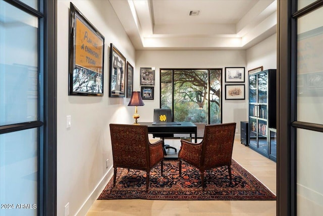 home office featuring a tray ceiling and hardwood / wood-style floors