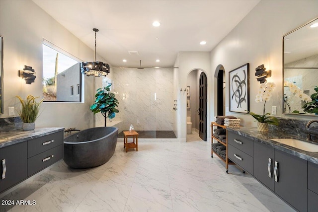 full bathroom featuring an inviting chandelier, toilet, tile walls, vanity, and independent shower and bath