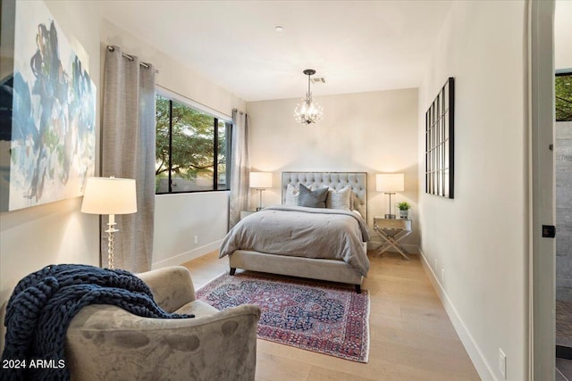 bedroom with an inviting chandelier and light hardwood / wood-style flooring