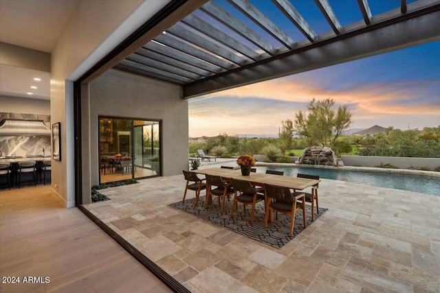 patio terrace at dusk featuring a mountain view, a pergola, and pool water feature