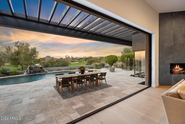 patio terrace at dusk with pool water feature and a large fireplace