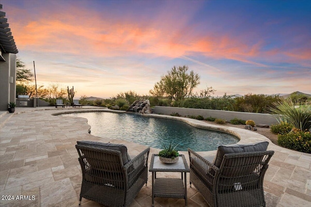 pool at dusk with a patio area