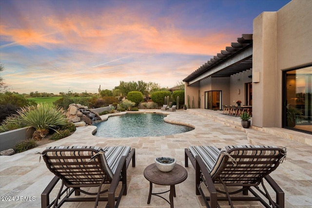 pool at dusk with a patio and pool water feature