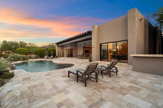 pool at dusk featuring a patio