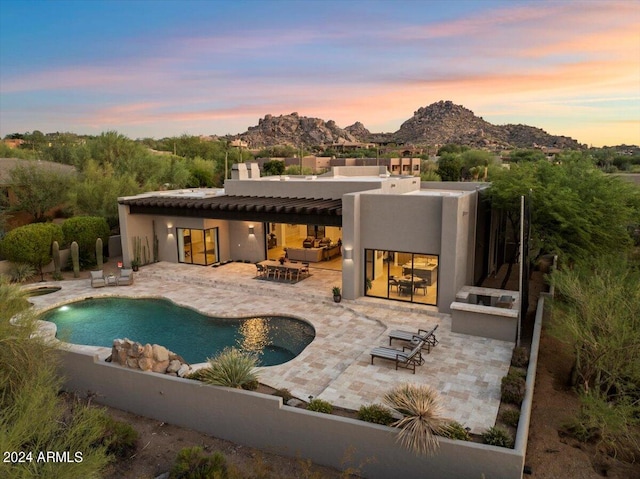 back house at dusk featuring an outdoor hangout area, a mountain view, and a patio area