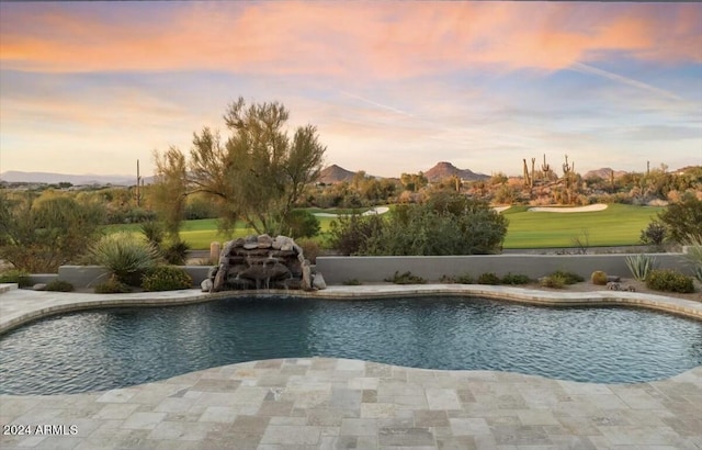 pool at dusk with a mountain view and a patio area