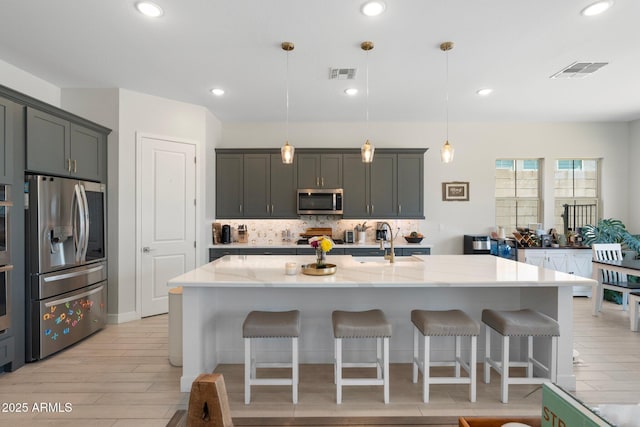 21134 W Minnezona Ave, Buckeye, AZ 85396 - kitchen featuring stainless steel appliances, a sink, tasteful backsplash, a breakfast bar, and light stone countertops
