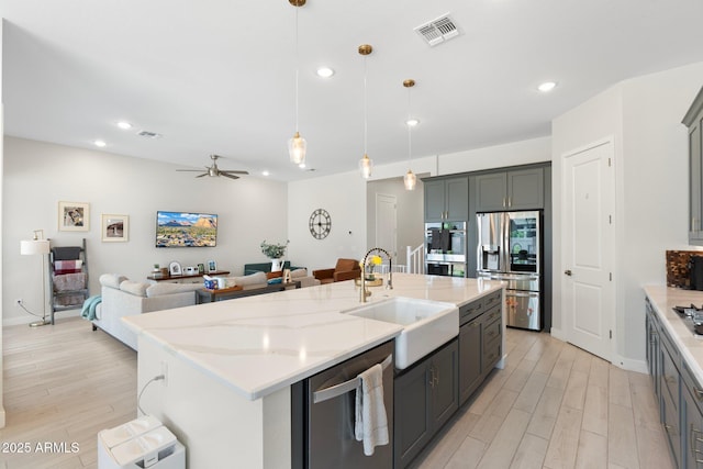 21134 W Minnezona Ave, Buckeye, AZ 85396 - kitchen with stainless steel appliances, a sink, open floor plan, recessed lighting, and light wood-style flooring