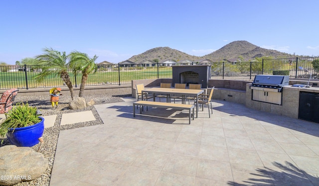 view of patio / terrace with exterior fireplace, a fenced backyard, area for grilling, grilling area, and outdoor dining space