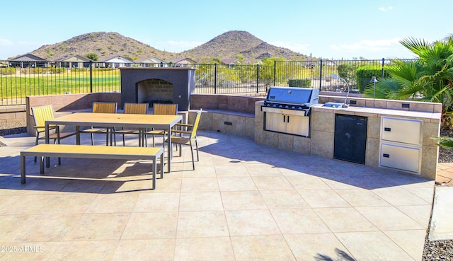 view of patio with outdoor dining space, a grill, an outdoor kitchen, and fence