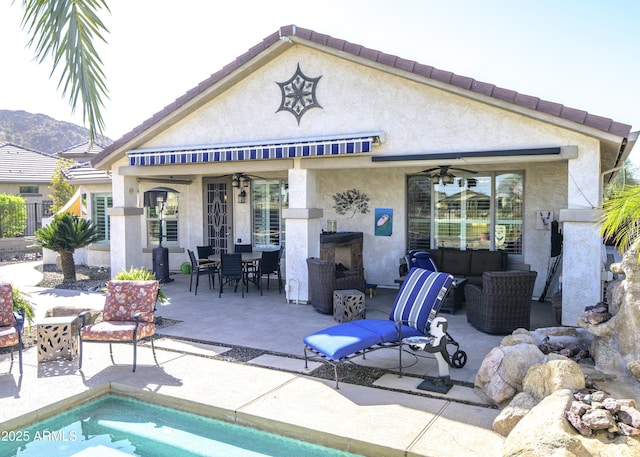 back of house with a patio, outdoor dining area, outdoor lounge area, a ceiling fan, and stucco siding