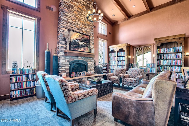 living room featuring a stone fireplace, a notable chandelier, a high ceiling, visible vents, and beam ceiling