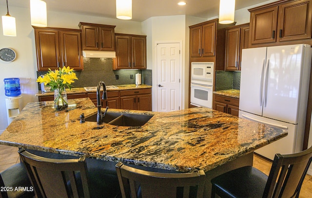 kitchen featuring white appliances, ventilation hood, a sink, and a breakfast bar