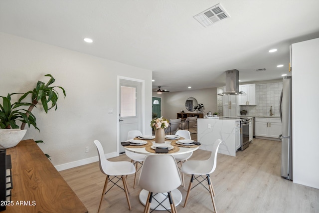 dining area with sink, ceiling fan, and light wood-type flooring