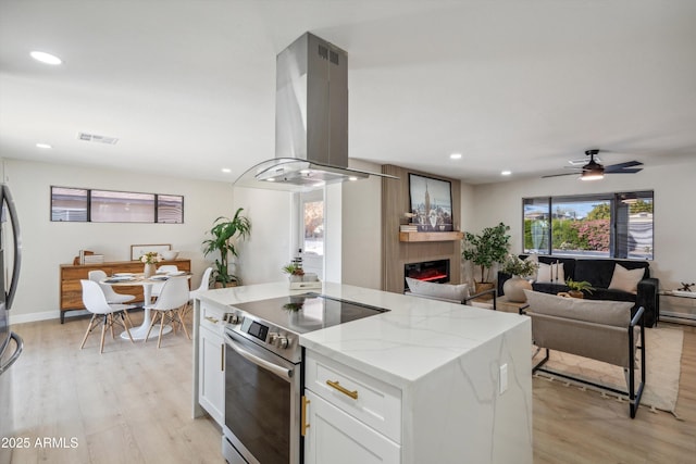 kitchen with light stone counters, appliances with stainless steel finishes, a kitchen island, island exhaust hood, and white cabinets