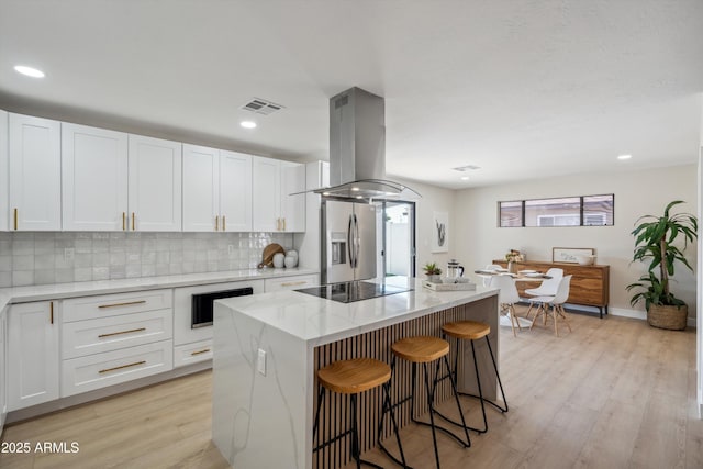 kitchen featuring white cabinetry, stainless steel fridge with ice dispenser, a kitchen island, and island exhaust hood