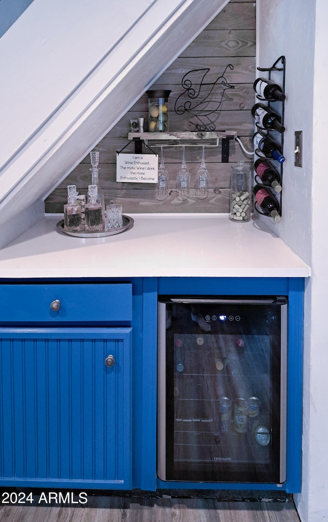 bar featuring wine cooler, blue cabinets, and dark hardwood / wood-style flooring