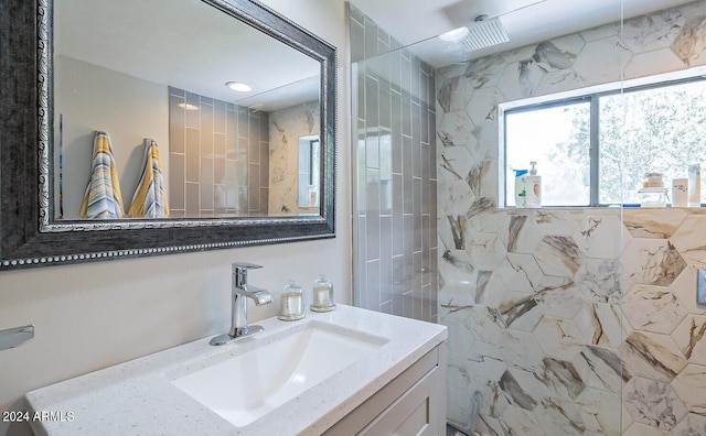 bathroom with a tile shower and vanity