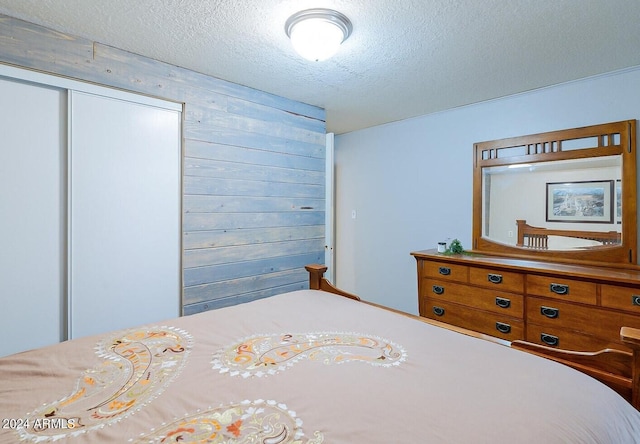 bedroom with a closet, wood walls, and a textured ceiling