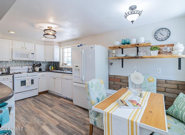 kitchen with white appliances, tasteful backsplash, wood-type flooring, sink, and white cabinets