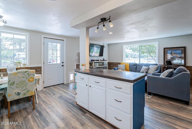 kitchen with dark wood-type flooring, white cabinets, a kitchen island, and a wealth of natural light