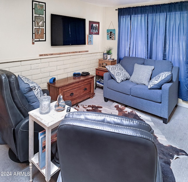 carpeted living room with brick wall