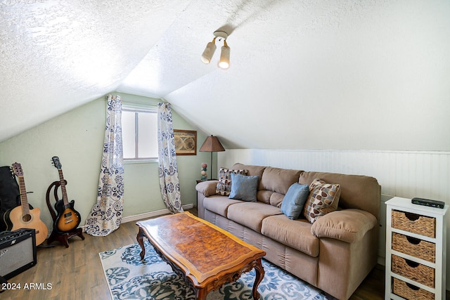 living room featuring vaulted ceiling, wood-type flooring, and a textured ceiling