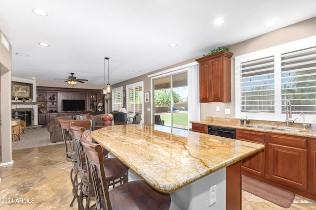 kitchen featuring ceiling fan, a fireplace, a center island, a breakfast bar, and sink