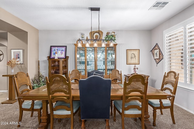 carpeted dining area featuring a notable chandelier