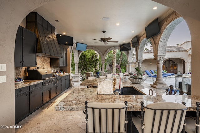 view of patio / terrace with a bar, an outdoor kitchen, area for grilling, and ceiling fan