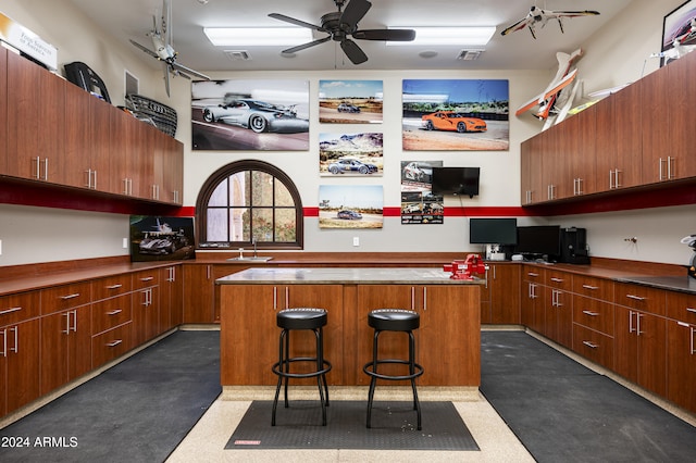 kitchen featuring a breakfast bar area, ceiling fan, a kitchen island, and built in desk