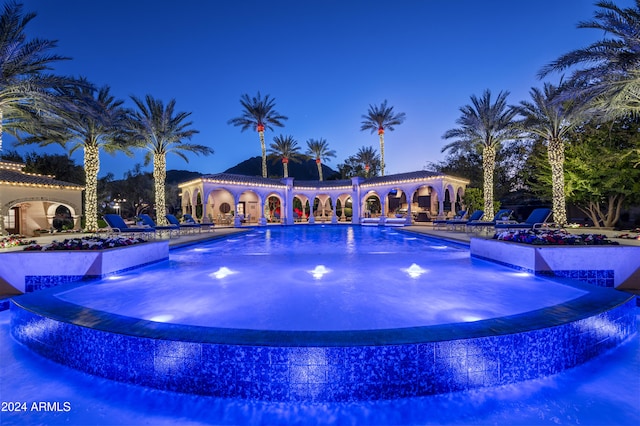 pool at dusk featuring pool water feature