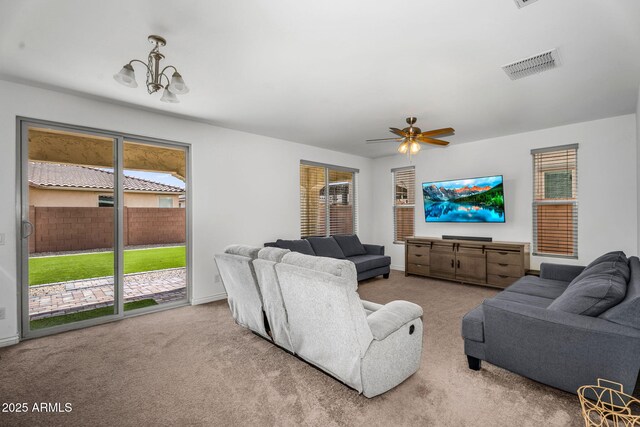 living room with carpet floors, ceiling fan with notable chandelier, and visible vents