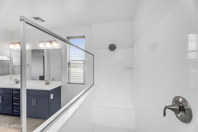 bathroom featuring vanity, walk in shower, and visible vents