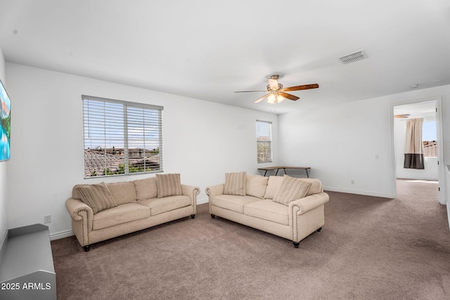living area with baseboards, visible vents, carpet, and a ceiling fan