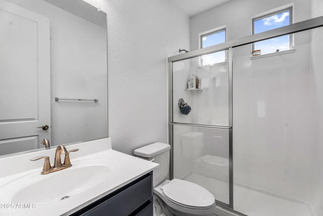 bathroom featuring toilet, a stall shower, and vanity