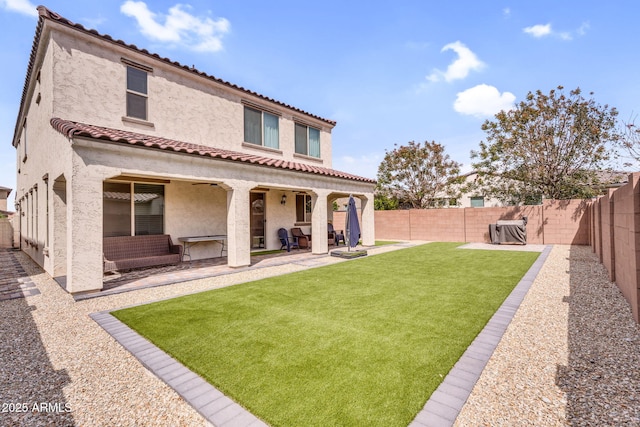 rear view of property with a fenced backyard, a tile roof, stucco siding, and a patio area