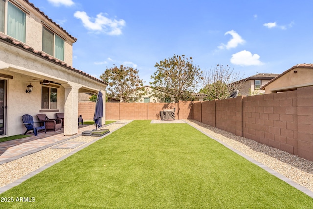 view of yard featuring a fenced backyard, ceiling fan, and a patio