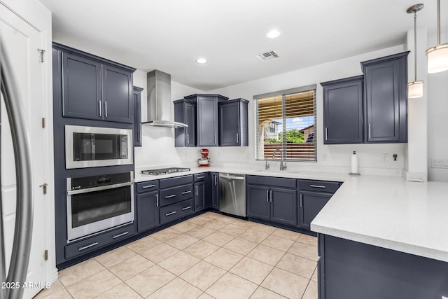 kitchen with light countertops, a sink, wall chimney exhaust hood, stainless steel appliances, and visible vents